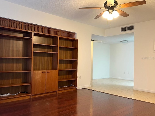 interior space with ceiling fan, wood-type flooring, and a textured ceiling