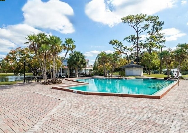 view of pool featuring a water view and a patio
