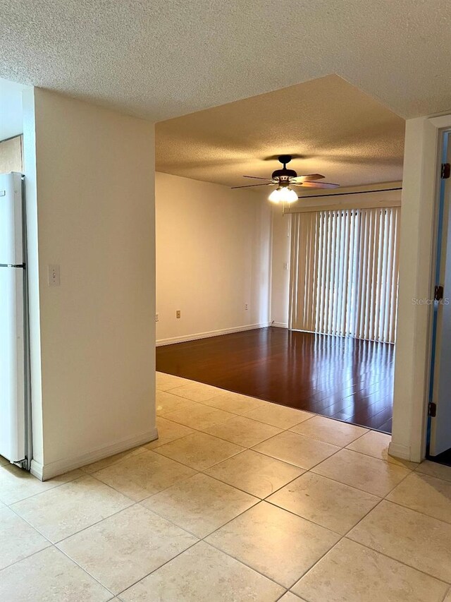 tiled spare room with ceiling fan and a textured ceiling