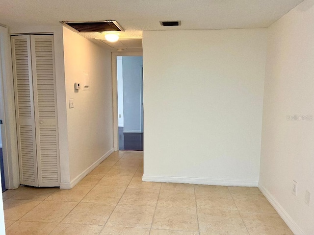 hallway featuring a textured ceiling and light tile patterned floors