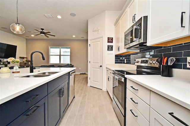 kitchen with appliances with stainless steel finishes, tasteful backsplash, sink, decorative light fixtures, and white cabinets