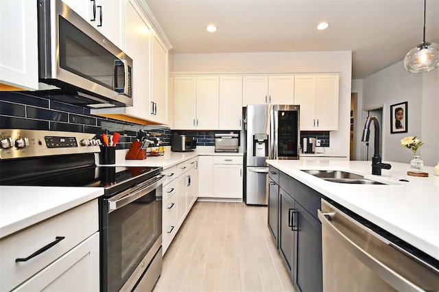 kitchen with decorative light fixtures, sink, white cabinetry, and stainless steel appliances