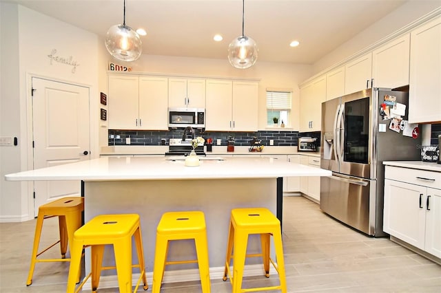 kitchen featuring pendant lighting, a kitchen bar, stainless steel appliances, and an island with sink