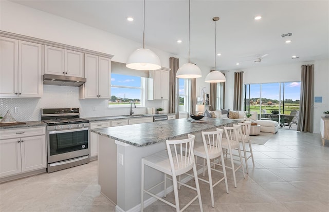 kitchen with stainless steel range, a center island, hanging light fixtures, and sink