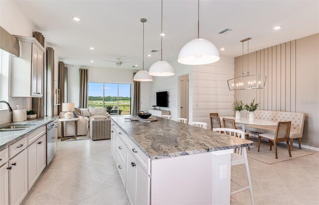 kitchen featuring a kitchen bar, a kitchen island, sink, white cabinetry, and hanging light fixtures