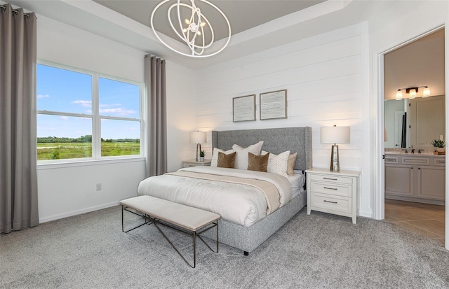 bedroom featuring a tray ceiling, connected bathroom, light tile patterned floors, and a chandelier