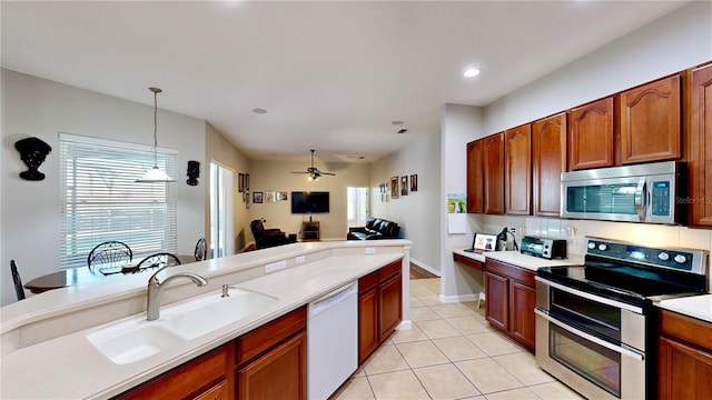 kitchen featuring pendant lighting, sink, light tile patterned floors, stainless steel appliances, and a healthy amount of sunlight