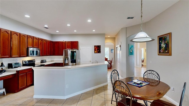 kitchen featuring a kitchen island with sink, hanging light fixtures, light tile patterned floors, and appliances with stainless steel finishes