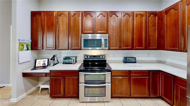 kitchen with appliances with stainless steel finishes, light tile patterned floors, and decorative backsplash