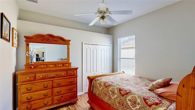 bedroom with ceiling fan, a closet, and light hardwood / wood-style flooring