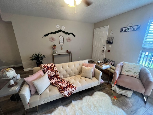 living room featuring dark wood-type flooring, a textured ceiling, and ceiling fan