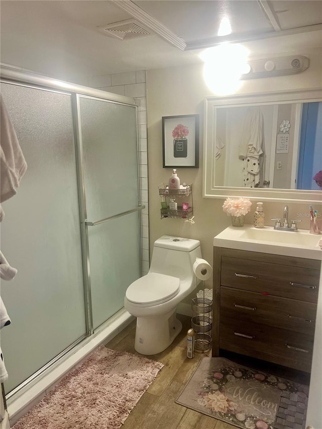 bathroom featuring toilet, hardwood / wood-style flooring, walk in shower, and vanity