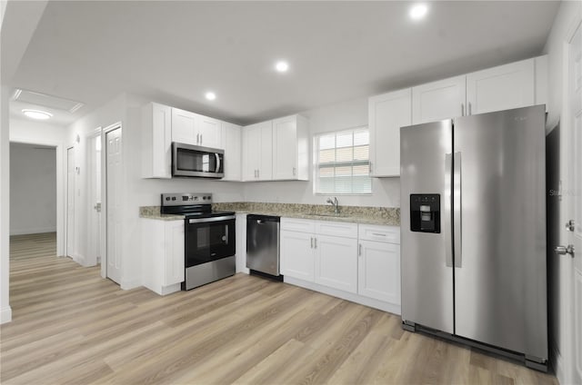 kitchen featuring white cabinets, light stone counters, stainless steel appliances, and a sink