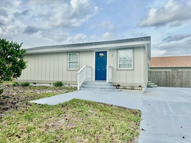 view of front of property with crawl space, board and batten siding, and fence