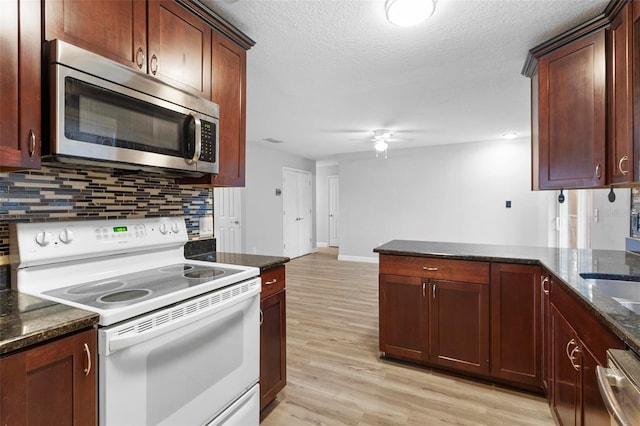 kitchen with stainless steel appliances, tasteful backsplash, light hardwood / wood-style floors, and dark stone countertops