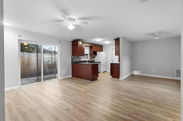 kitchen featuring ceiling fan, white fridge, light hardwood / wood-style flooring, and tasteful backsplash