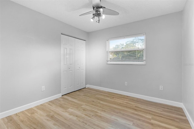 unfurnished bedroom with a textured ceiling, a closet, light hardwood / wood-style flooring, and ceiling fan