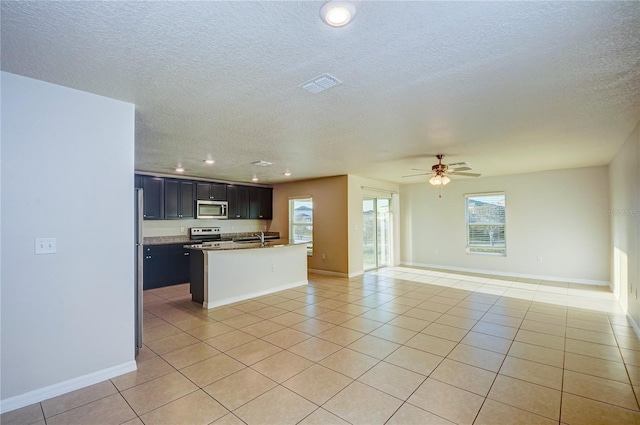 kitchen with a kitchen island, light tile patterned flooring, ceiling fan, and appliances with stainless steel finishes