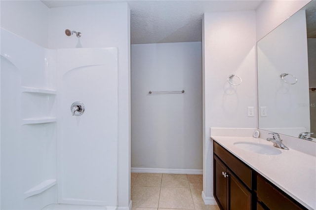 bathroom with vanity, tile patterned flooring, a textured ceiling, and a shower