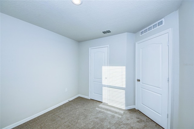 carpeted spare room featuring a textured ceiling