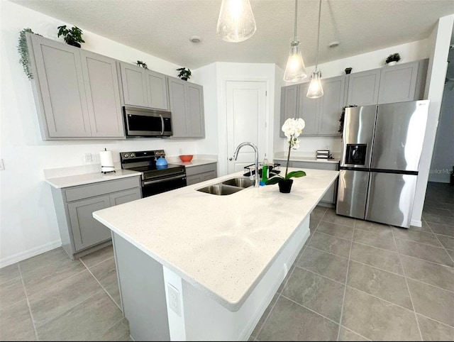 kitchen with hanging light fixtures, a kitchen island with sink, sink, and stainless steel appliances