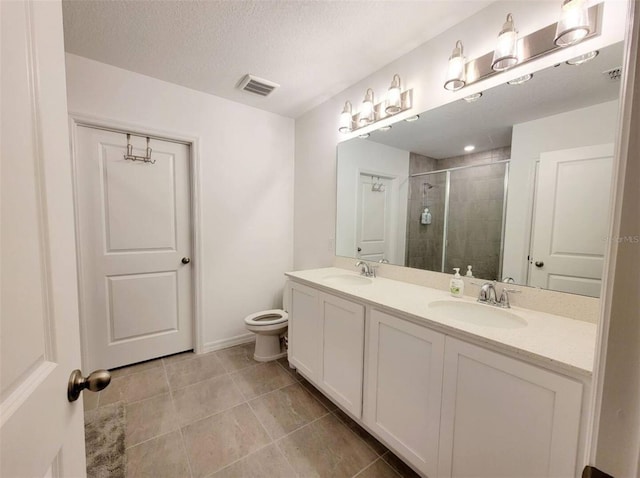 bathroom with vanity, toilet, a shower with shower door, and a textured ceiling