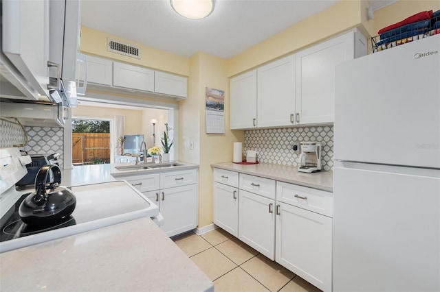 kitchen featuring white cabinetry, sink, tasteful backsplash, white fridge, and light tile patterned floors