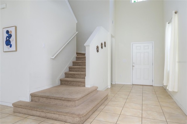 stairs with tile patterned floors and a towering ceiling