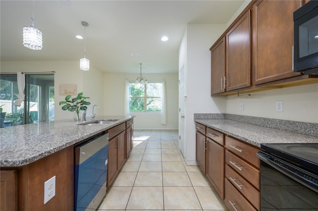 kitchen featuring light stone counters, a kitchen island with sink, sink, black appliances, and pendant lighting