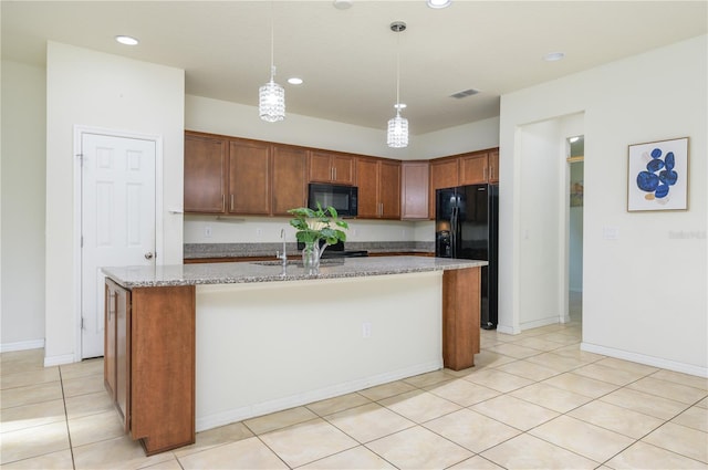 kitchen with light stone counters, sink, black appliances, a center island with sink, and hanging light fixtures