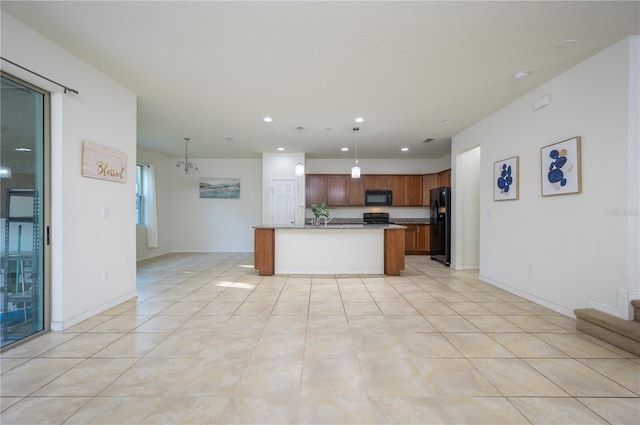 kitchen with light stone counters, pendant lighting, a kitchen island with sink, light tile patterned floors, and black appliances