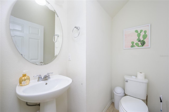 bathroom with toilet, vaulted ceiling, and sink