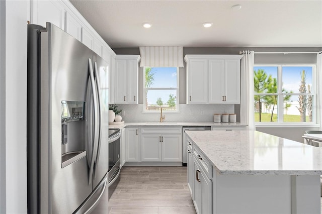 kitchen with a wealth of natural light, sink, white cabinets, and appliances with stainless steel finishes