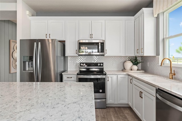 kitchen featuring white cabinetry, sink, light stone counters, and appliances with stainless steel finishes