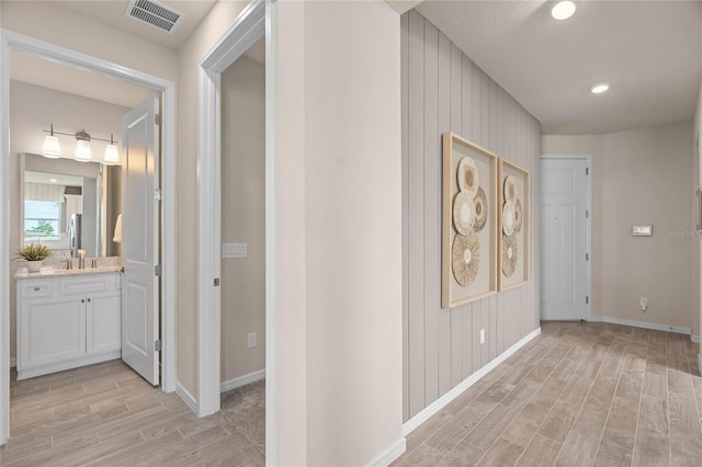 hallway with sink and wood walls