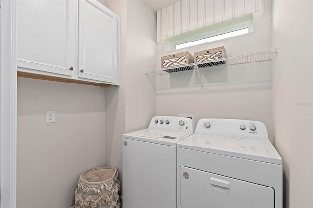 clothes washing area with cabinets and washer and clothes dryer