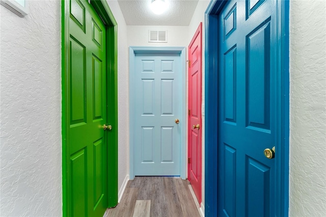 doorway to outside with light hardwood / wood-style flooring and a textured ceiling