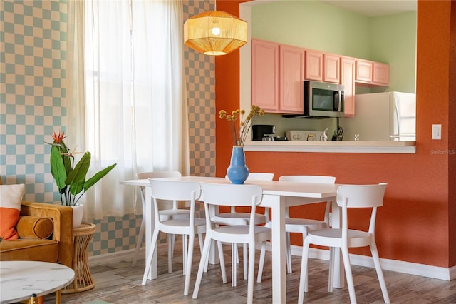 kitchen with light brown cabinets, white refrigerator, hardwood / wood-style flooring, and pendant lighting