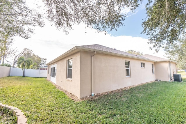 view of side of home featuring a lawn and central AC