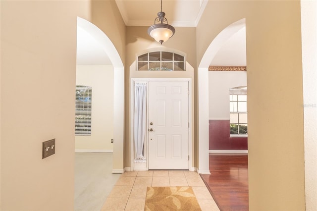 entrance foyer featuring light tile patterned flooring, crown molding, and a high ceiling