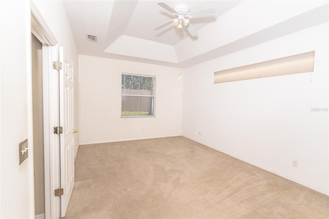 carpeted spare room with a tray ceiling and ceiling fan