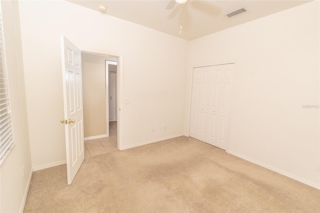 unfurnished bedroom featuring a closet, ceiling fan, and light colored carpet