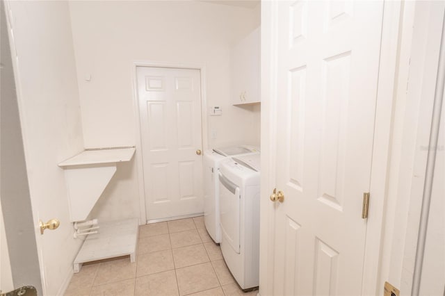 laundry room with washing machine and clothes dryer, light tile patterned flooring, and cabinets