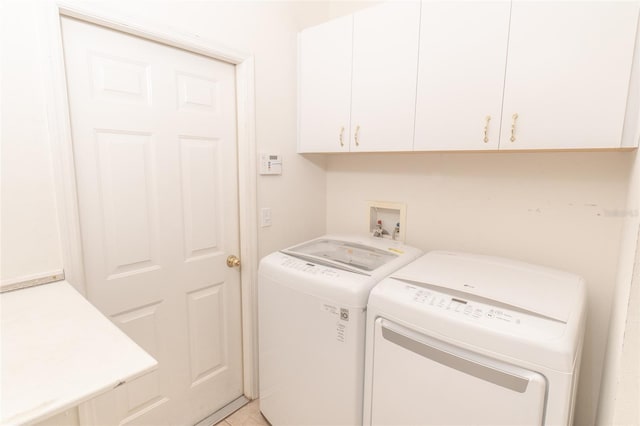 laundry area with tile patterned floors, washer and dryer, and cabinets