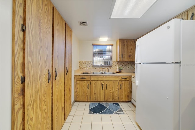 kitchen with light tile patterned flooring, a sink, visible vents, light countertops, and freestanding refrigerator