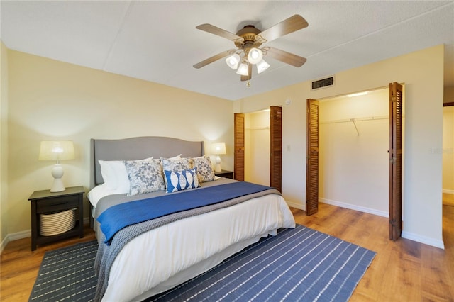 bedroom with baseboards, visible vents, ceiling fan, and wood finished floors