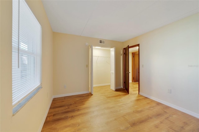 empty room featuring visible vents, light wood-style flooring, and baseboards