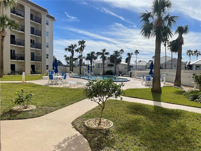 view of property's community featuring a yard, a swimming pool, a patio area, and fence