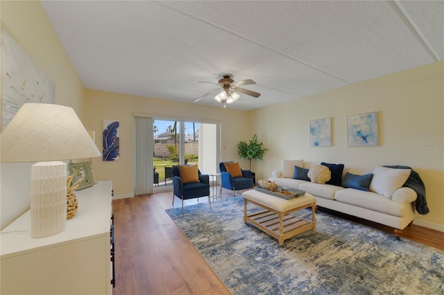 living area with a textured ceiling, wood finished floors, a ceiling fan, and baseboards