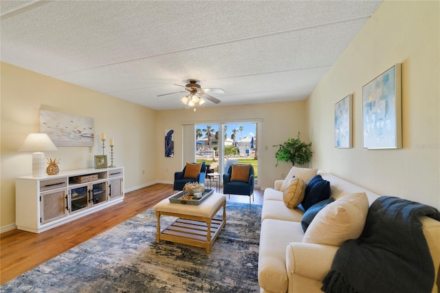 living room featuring a textured ceiling, baseboards, and wood finished floors